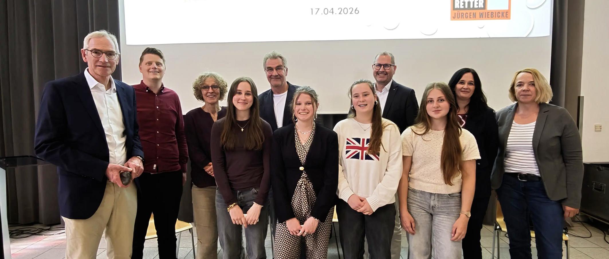 Bildunterschrift: Demokratie im Dialog: Ines Philipen, Elisabeth Anlauf, Nila Küppers und Paula Philipen, Schülerinnen der Jahrgangsstufe 10 des Gymnasiums St. Ursula, gestalteten gemeinsam mit Autor Jürgen Wiebicke eine lebhafte Diskussion über gesellschaftliche Verantwortung und demokratische Werte. Auf dem Bild (v. l.): Schulleiter Jürgen Pallaske, Lehrer Sebastian Tschakert, Mechtild Bose, Jürgen Wiebicke, Ulrich Paus, Judith Anlauf, Sylke Kreyes vom Caritasverband sowie die vier moderierenden Schülerinnen.